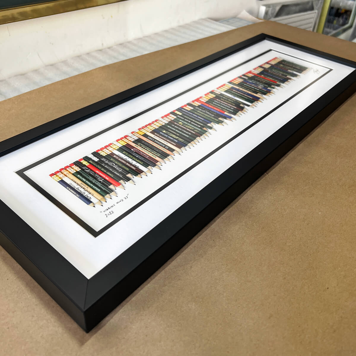 A framed golf art piece featuring a collection of golf pencils from all the 82 golf courses Tiger Woods won on the PGA TOUR. 