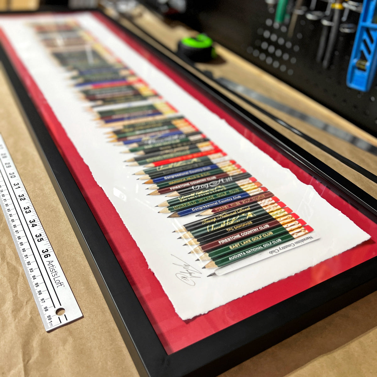A framed golf art piece featuring a collection of golf pencils from all the 82 golf courses Tiger Woods won on the PGA TOUR. 